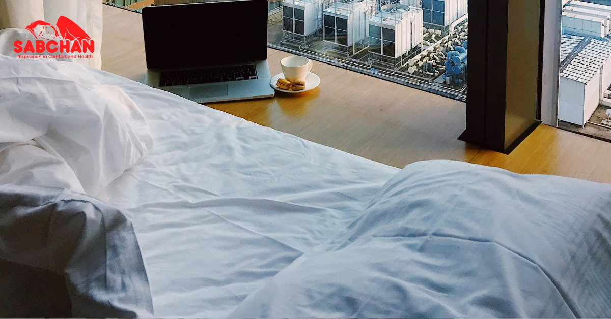 Kasur ukuran single dengan bantal didekat laptop